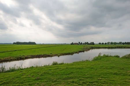 Canal along a dike under dark cloudsの写真素材