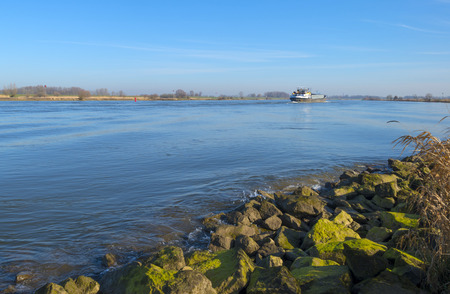 Barge sailing on a river under a blue sky in winterの写真素材