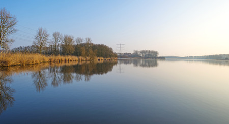 The shore of a foggy lake in winter at dawnの写真素材