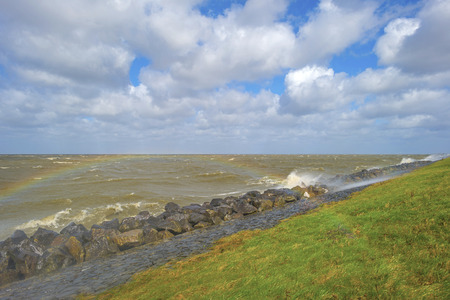 Storm raging over a lake along a dike in spring