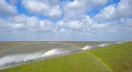 Storm raging over a lake along a dike in spring