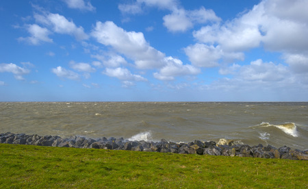 Storm raging over a lake along a dike in spring