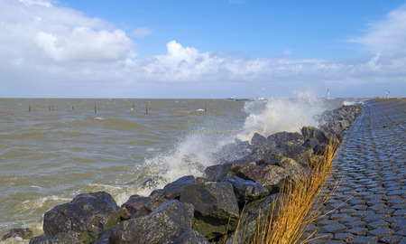 Storm raging over a lake along a dike in spring