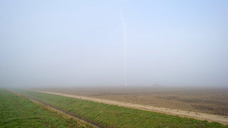 Wind turbine in a foggy field in springの写真素材