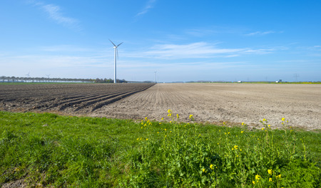 Wind turbine in a plowed field in springの写真素材