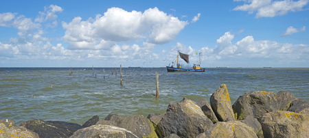 Trawler fishing in a lake along a dike