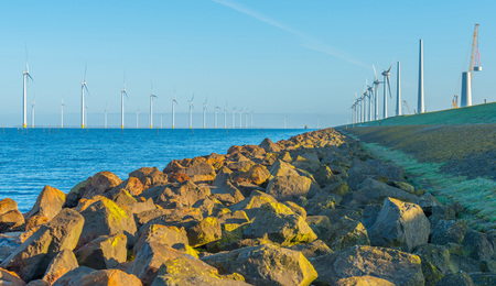 Wind turbines under construction along a dike