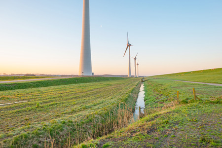 Wind turbines along a dike at sunrise