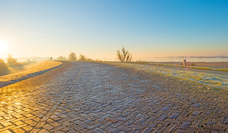 Dike along a frozen lake at sunriseの写真素材