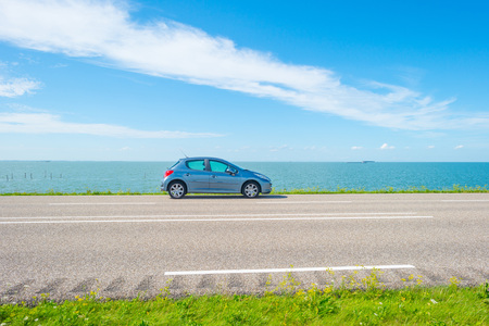 Car parked on a dike along the shore of a lake in summerの写真素材