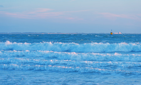 Sea along a sandy beach in the light of sunset in summer