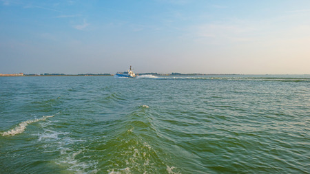 Boat sailing on a lake at sunset in summerの写真素材