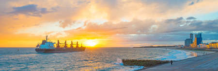 Boat sailing at sea along a coast at sunset in summer