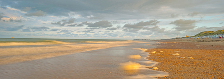 Sea along a sandy beach in the light of sunrise in summerの写真素材