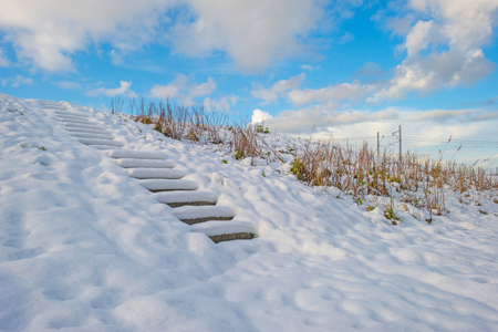 Snowy stairway on a frozen hill in sunlight in winterの写真素材