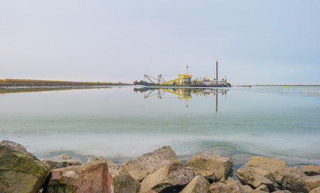 Edge of a frozen lake along a dike in winterの写真素材