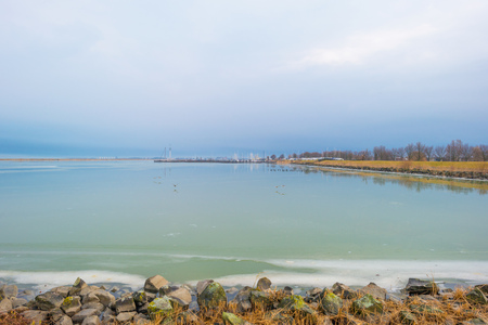 Edge of a frozen lake along a dike in winterの写真素材