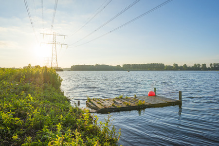 Power line on a lake along a lake at sunrise in springの写真素材