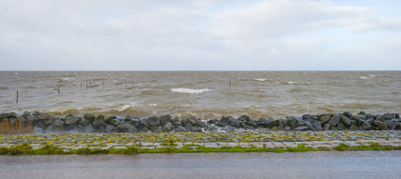 Dike along a stormy lake in sunlight in winter