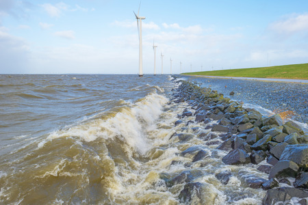 Wind farm in a stormy lake in sunlight in winter