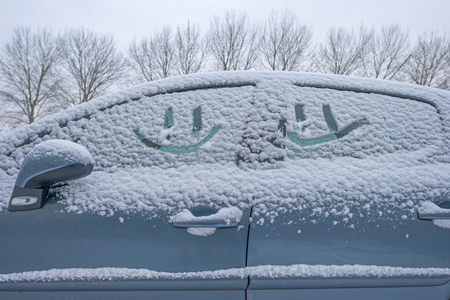 Smiley car in the snow in a street along trees in winterの写真素材