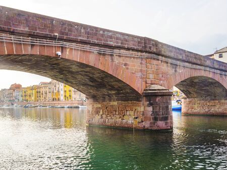 Panorama of the colorful town of Bosa along a river and hills in sunlight in springの写真素材