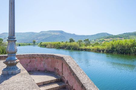 Panorama of the colorful town of Bosa along a river and hills in sunlight in springの写真素材