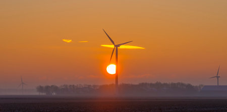 Wind turbine in an agricultural field in sunlight at sunrise in an early winter morning, Almere, Flevoland, The Netherlands, January 31, 2021の写真素材