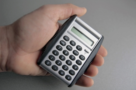 calculator in human hand in front of grey surfaceの写真素材