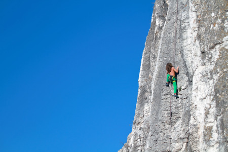 Young boy rock climber in search of for his next gripの写真素材