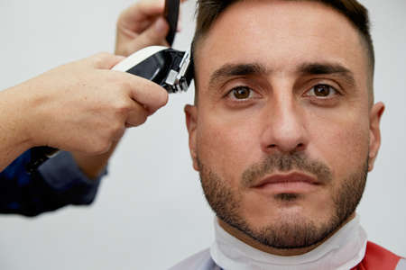 Close-up of a barber working on a customer's hair in the salon with a razorの写真素材