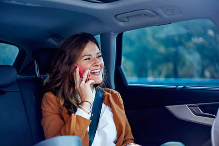 Caucasian woman using her cell phone in a car - Business woman smiling, talking on her cell phoneの写真素材