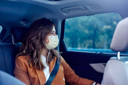 Caucasian woman with a face mask traveling in a car - Woman on business tripの写真素材