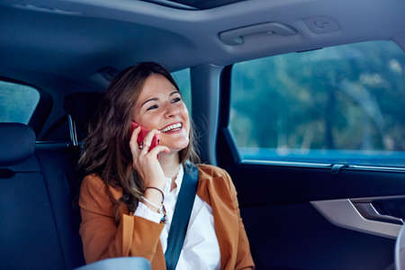 Caucasian woman using her cell phone in a car - Business woman smiling, talking on her cell phoneの写真素材