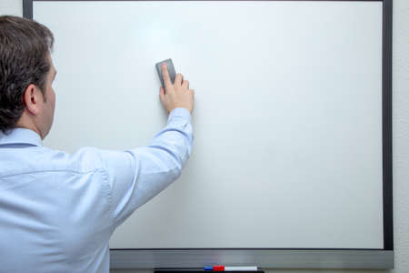 Adult man with shirt erasing on white boardの写真素材