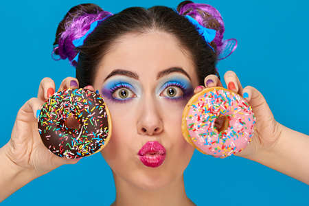 Pretty girl with red lips and hair up from eating a donuts, wearing colorful makeup