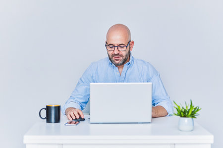 Business man teleworking from home with a laptop and talking on a cell phone.の写真素材