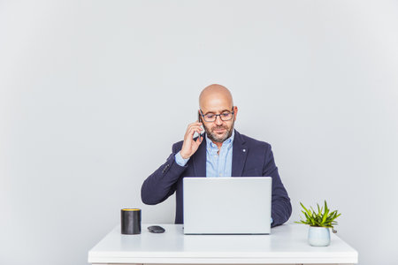 Business man teleworking from home with a laptop and talking on a cell phone.の写真素材
