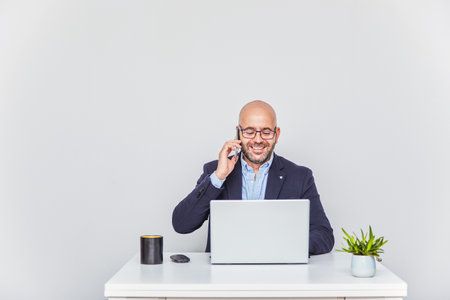 Business man teleworking from home with a laptop and talking on a cell phone.の写真素材