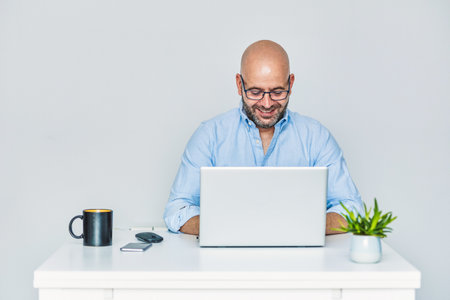 Business man teleworking from home with a laptop and talking on a cell phone.の写真素材