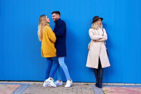 A Couple in loving attitude next to an angry girl. Concept of couple and lack of love