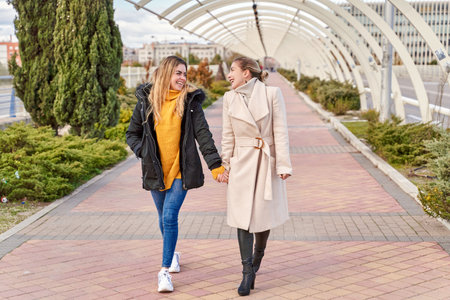 Happy and positive moments of two elegant girls walking down the street in the city. Portrait of young girls having fun, smiling, charming moments, best friend. Concept of friendship and loveの写真素材