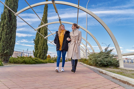 Happy and positive moments of two elegant girls walking down the street in the city. Portrait of young girls having fun, smiling, charming moments, best friend. Concept of friendship and loveの写真素材