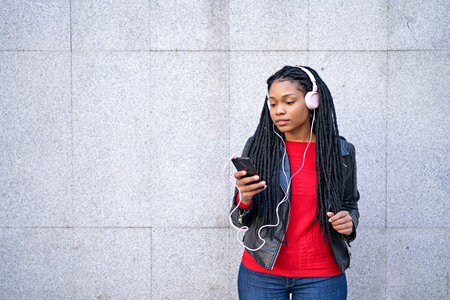 A portrait of a smiling African-American woman with a cell phone is chatting or listening to music...