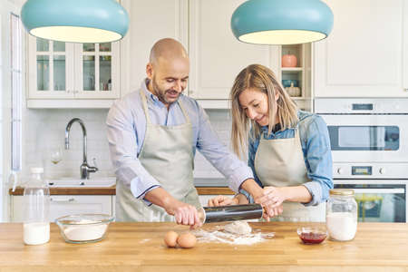 Happy couple cooking at home. Preparing pizza dough. Couple cooking concept.の写真素材