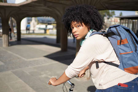 Latina woman riding a bicycle in the city. African American woman using green transportationの写真素材