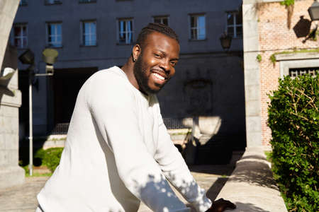 Young African American man smiling leaning against a wall, Happy Latino man.の写真素材
