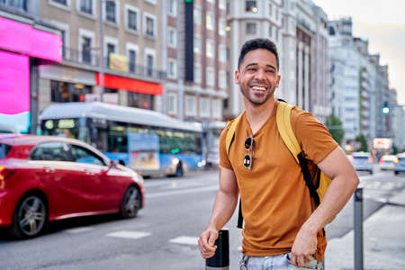 Young smiling Latino man walking through the streets of Madrid. Walking down main street of the city.の写真素材