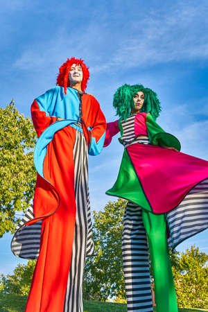 Creative stilt walkers with umbrella and sword performing show in parkの写真素材