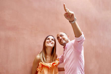 Happy couple pointing up in streetの写真素材